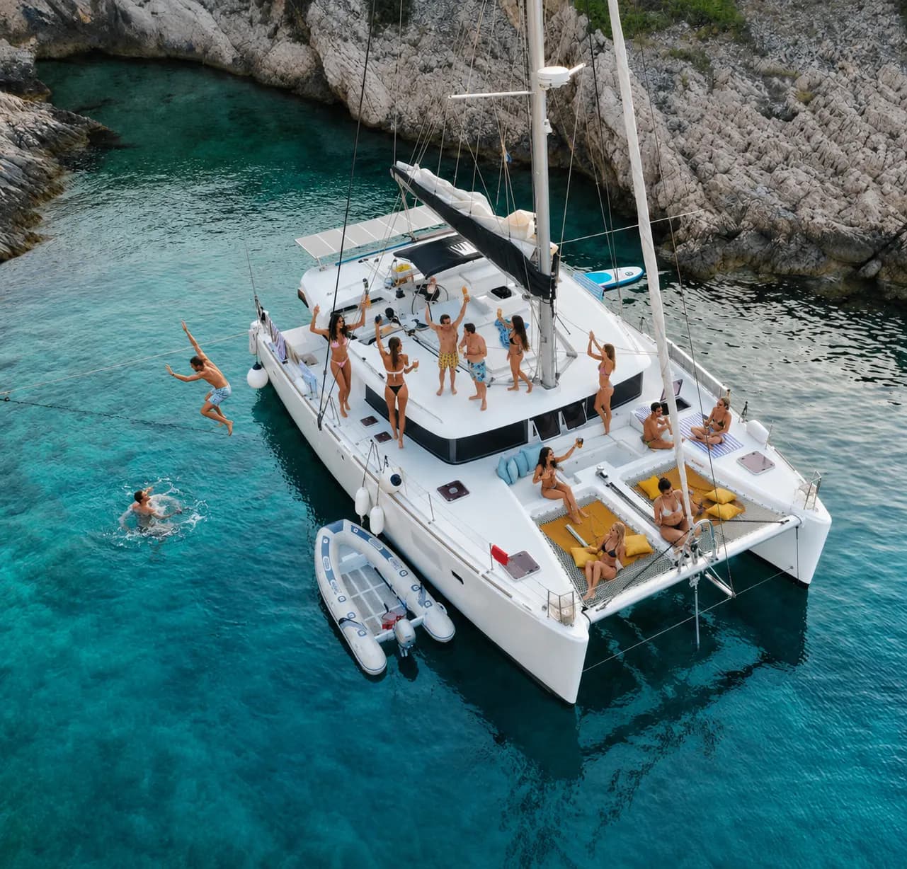 Friends celebrate aboard a private catamaran in a clear coastal cove